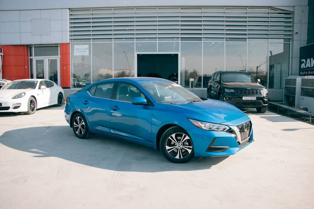 Berline bleue d’occasion sur le parking d’un vendeur